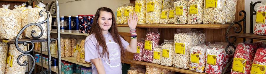 Katie gesturing to shelves of bagged popcorn